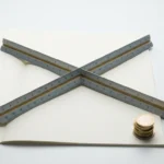 Architectenlineaal diagonaal op een open contractdocument met een stapeltje euromunten, minimalistisch bovenaanzicht.