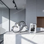 Chrome AWS logo sculptuur op wit marmeren bureau naast ingelijste portretfoto, moderne kantooromgeving met geometrische schaduwen
