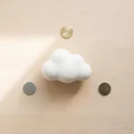 Witte keramische wolk zweeft boven houten bureau met drie gouden munten in geometrische opstelling, warme natuurlijke belichting