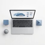 Moderne laptop met cloud storage iconen op scherm op witte bureau omringd door geometrische vormen in minimalistisch ontwerp