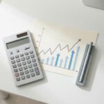 Moderne calculator en financiële grafiek met stijgende trend op wit bureau, minimalistisch werkplek design