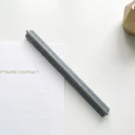 Architectenlineaal liggend op een IBM softwarecontract op wit bureau, met klein vetplantje, vlakke bovenaanzichtfoto.