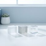 Drie geometrische kubussen in lijn op wit bureau, variërend van ondoorzichtig naar transparant, minimalistische kantooromgeving