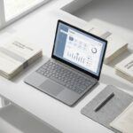Moderne laptop met dashboard-interface op wit bureau, omringd door softwarelicentie-documenten en pen, natuurlijk licht