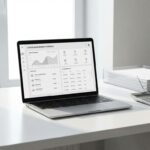 Moderne laptop met digitaal licentie dashboard op wit bureau naast contractdocumenten en rekenmachine in minimalistisch kantoor