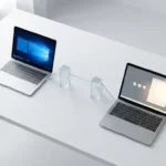 Twee laptops op witte bureau verbonden door glazen geometrische brug, bovenaanzicht met natuurlijk licht