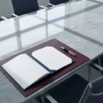 Openliggend contract en vulpen op grijs marmeren onderhandelingstafel met geometrische schaduwen in marineblauw en zilver.