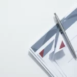 Zilverkleurige pen op SAP-contractdocument met gevouwen rode hoeken als waarschuwingssignalen, strak bovenaanzicht op wit bureau.
