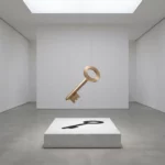 Gouden SAP-licentiesleutel zweeft boven wit marmeren voetstuk in minimalistische galerieruimte met geometrische schaduw