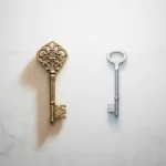 Sierlijke messing sleutel naast een strakke zilveren sleutel op grijs oppervlak, overhead flatlay met contrast tussen klassiek en modern design.