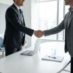 Professionele handdruk tussen interim-koper en teamlid aan moderne vergadertafel in minimalistisch kantoor